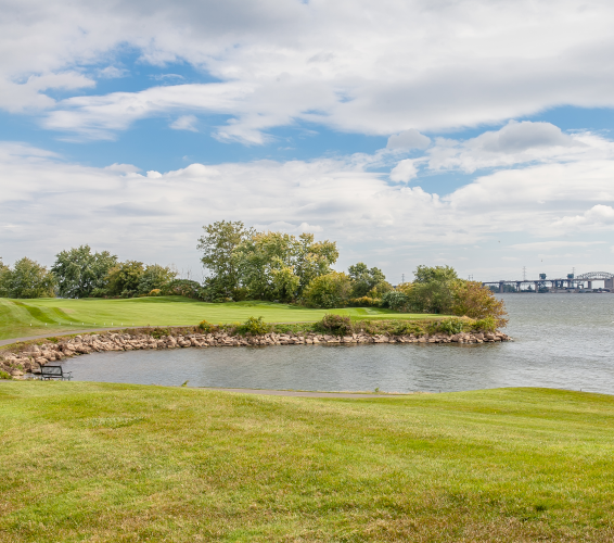 grassy field and edge of ocean with city in distance