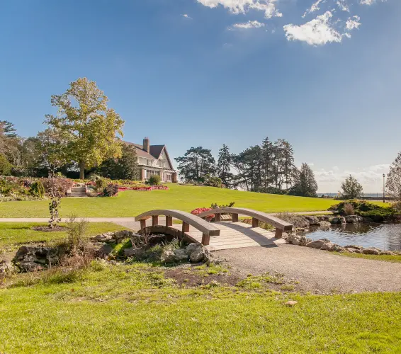 managed yard and pond with bridge over creek. Home in the background